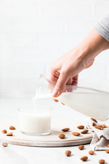 Female hand pours Almond milk from a bottle .Drink for vegetarians.