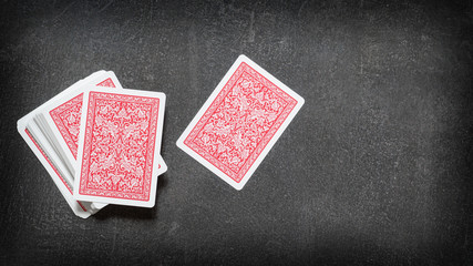 Deck of playing cards and one card separately face down on a black table