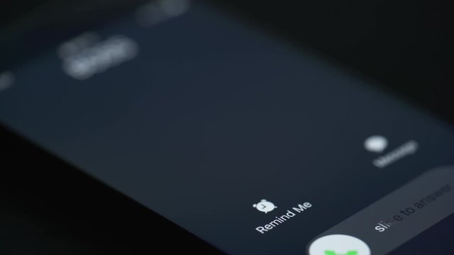 Detailed view: Incoming call by Boss on the smartphone screen. Focus moving to Remind me. Early morning, dark room.