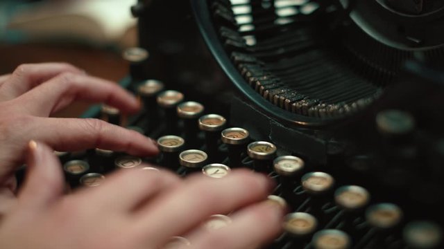 Woman's hands typing on an isolate vintage underwood typewriter. The attractive hands move across the retro keys of the type writer and you can see the strikers moving up and down.