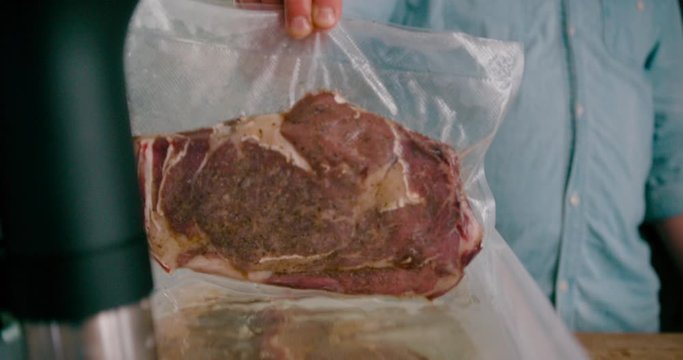 Low angle view of a man taking out the vacuum-sealed steak package form the Sous Vide Precision Cooker.