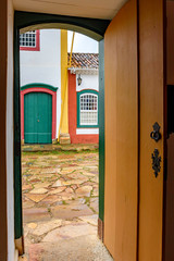 Stone street and antique houses seen through an old wooden door in the historic town with 18th century colonial architecture of Tiradentes in the state of Minas Gerais