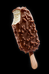 Chocolate coated ice cream with crisps on a stick on a black background