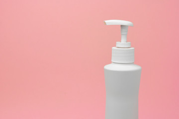 Mock up of white bottle with a dispenser on a pink background. Blank for skincare products