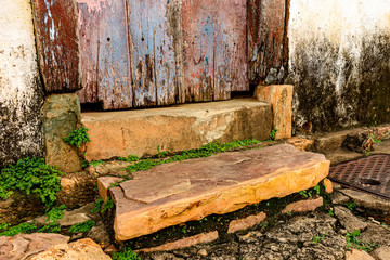 Wooden door and stairs and stone sidewalk in an old house of colonial architecture deteriorated by time in the historic city of Tiradentes in Minas Gerais