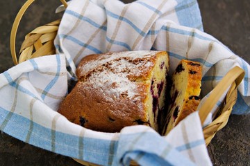 Cake with a fragrant black currant, sprinkle with powdered sugar in a brown wicker basket on...