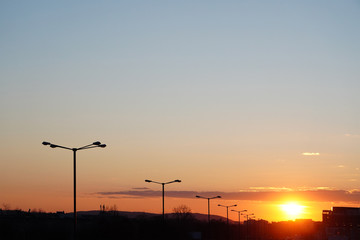 Beautiful sunset over the city. The road at sunset. Cars drive along a city street in the rays of the setting sun