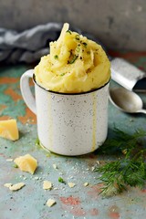 Mashed potatoes with butter and olive oil, greens and parmesan slices on a gray background, Bowl, cup of mashed potatoes puree