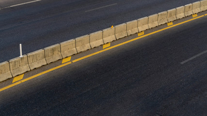 Fototapeta premium The road built from asphalt separating left and right with yellow lines and cement barricades