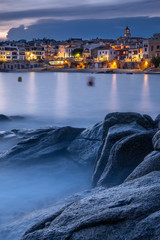 Pueblo marítimo de Calella de Palafrugell de la Costa Brava al atardecer con rocas en primer plano...
