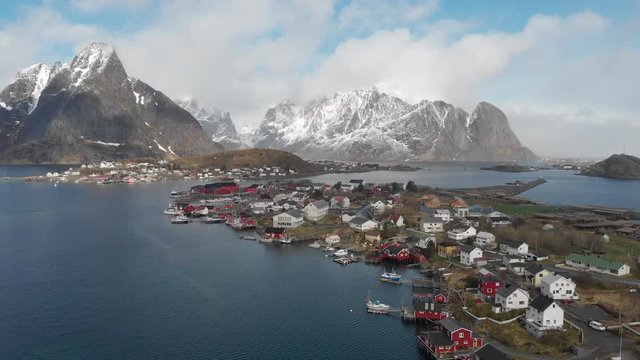 Areal view from the air of Reine on the Lofoten Islands with red cottages in the foreground and snow covered mountains in the background