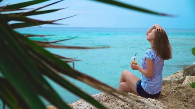 Woman enjoying Frappe Coffee on Latchi Adams Beach in Ayia Napa, Cyprus.