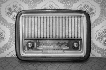 An old transistor radio, with knobs and buttons for manual tuning. In the background a vintage...