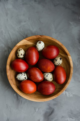 Easter concept. Natural Easter eggs in a wooden bowl cooked in onion peels on a dark stone background. Vertical orientation. Selective focus. Top view.