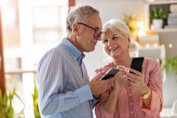 Senior couple looking at a smartphone together at home