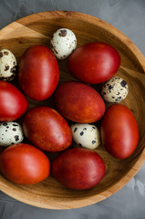 Easter concept. Natural Easter eggs in a wooden bowl cooked in onion peels on a dark stone background. Vertical orientation. Selective focus. Top view. Close up