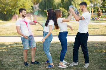 Friends with a holi paints. People in a summer park. Students have fun.