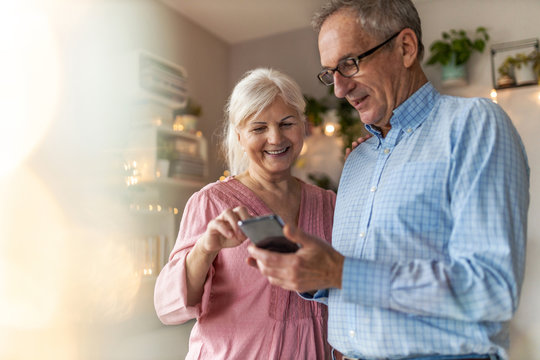Senior couple looking at a smartphone together at home