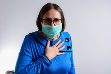 Unhappy brunette woman having breath difficulties in front of white background. A young woman have shortness of breath holding her breast in pain