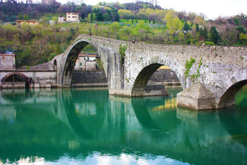 The suggestive and famous Ponte del Diavolo of Lucca built in bricks over a river in an ancient medieval village in Borgo a Mozzano