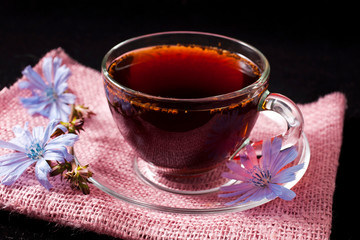 Diet drink chicory in a cup. Coffee substitutes with Cichorium intybus flower on a black background.