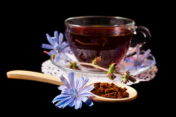 Diet drink chicory in a cup. Coffee substitutes with Cichorium intybus flower on a black background.