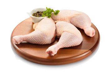 Primal cut of raw chicken legs, with chicken thighs and drumsticks, on a wooden cutting board....