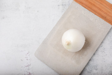 Whole White Onion on Cement Cutting Board on Cement Countertop