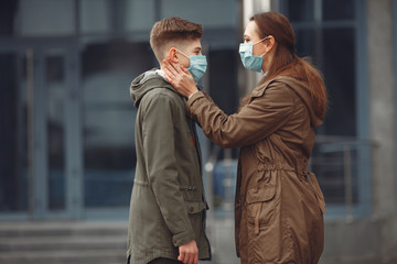 A boy and mother are wearing protective masks. The kid is sneezing and mother is helping him to wear a piece of protective equipment.