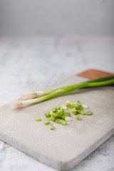 Whole and Chopped Green Onions on Cement Cutting Board on Cement Countertop