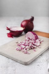 Whole and Chopped Red Onions on Cement Cutting Board on Cement Countertop