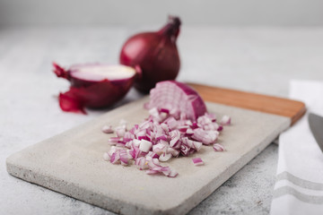 Whole and Chopped Red Onions on Cement Cutting Board on Cement Countertop