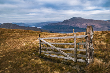 Old weathered wooden gate near the top of Beinn Dubh in Scottish Highlands on a cloudy morning, wide angle landscape.