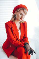 Beautiful fashion model in red suit, Woman in red hat, Red lipstick . Portrait of glamour blonde girl with bright makeup. 