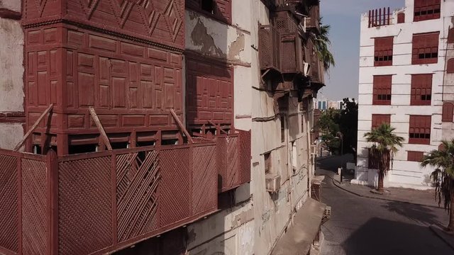 Drone flight past historic merchant houses made of coral stones and carved wood in Jeddah (two pigeons fly away in the shot)