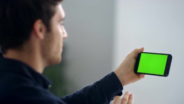 Cheerful making video talk on green screen mobile phone in slow motion