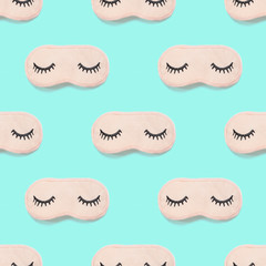 Seamless pattern from pink sleep mask with closed eyes embroidered on it with eyelashes on turquoise background. Photographic collage. Top view, flat lay. Accessories for girls and young women