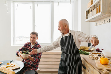 Young man and his father cooking in kitchen