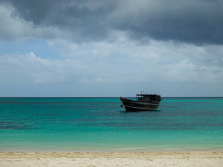 Fototapeta na wymiar Wooden boat off the coast of Zanzibar island, against a background of dark sky and clouds before the rain