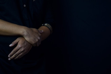 Young man praying with arms across posture. Islamic praying concept on black background. Selective focus on finger