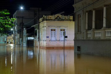 Vista noturna de casarões antigos e ruas alagadas por enchente do Rio Pomba, no centro de Guarani, estado de Minas Gerais, Brasil em março de 2020