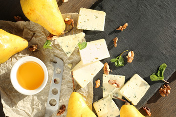 Yellow pears, cheese, honey nuts, mint on a dark background