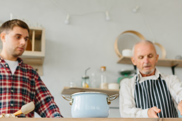 Young man and his father cooking in kitchen