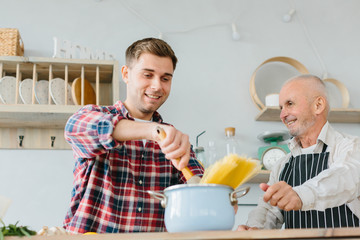 Young man and his father cooking in kitchen