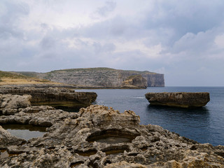 The stone coast on the island of Malta and pieces of rock in the waters of the Mediterranean Sea