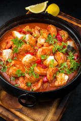 Traditional American fish stew cioppino with prawns, and fish as closeup in a modern design cast-iron roasting dish