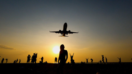 Naklejka na ściany i meble Passenger plane flying close to the ground. People standing on the beach close to flying planes