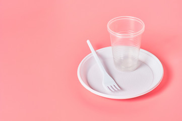 Disposable plastic utensils on pink background. Concept of save environment, ecology, recreation on picnic, party and other events. Copy space