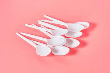 White disposable spoons on pink background. Concept of save environment, ecology, recreation on...