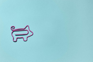 top view of pink decorative piggy paper clip on blue background with copy space